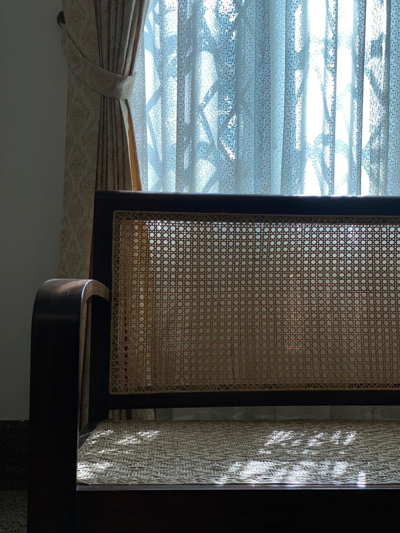 A caned wooden bench beside a window, morning light falling across the seat